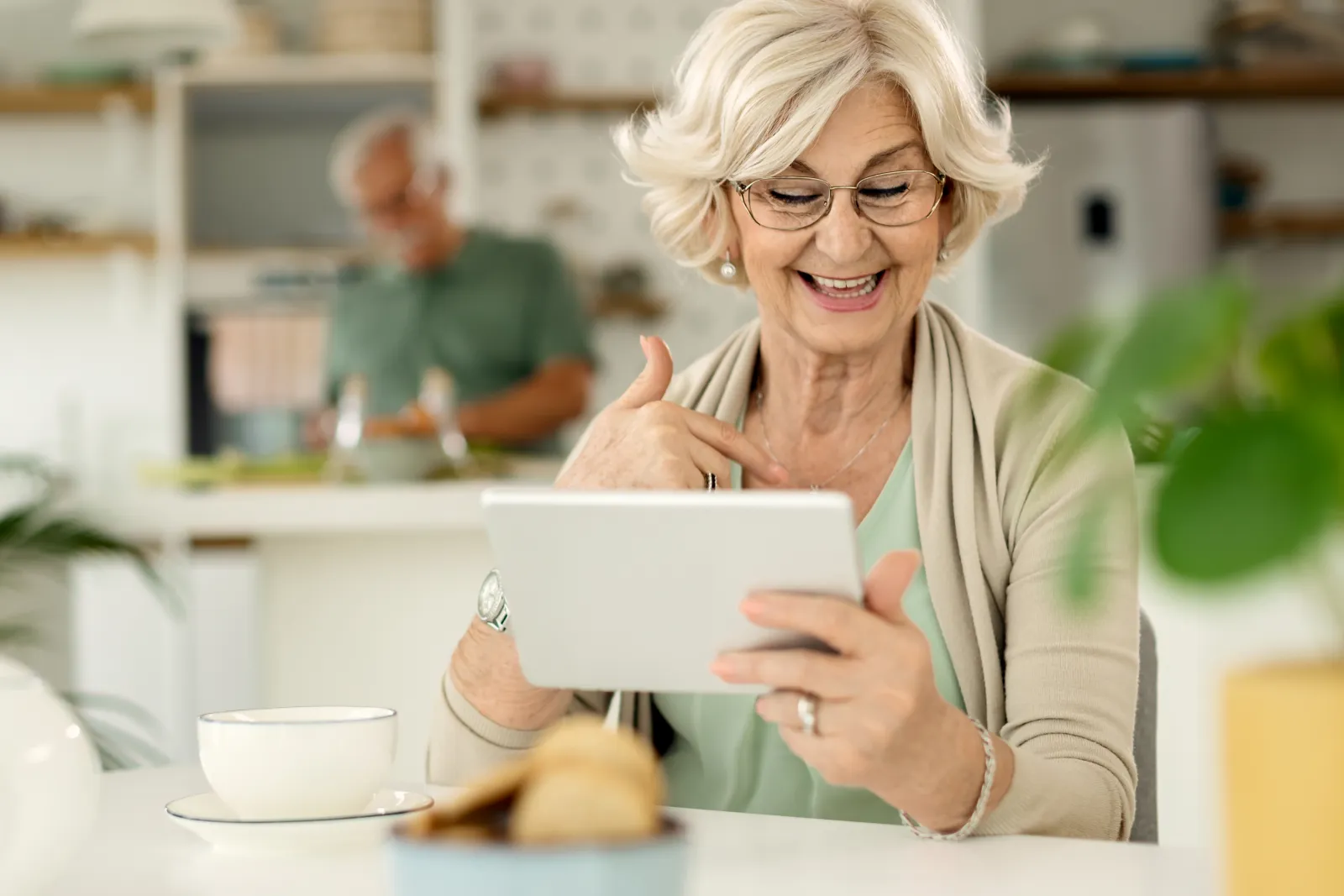 Senior at home smiling while using tablet