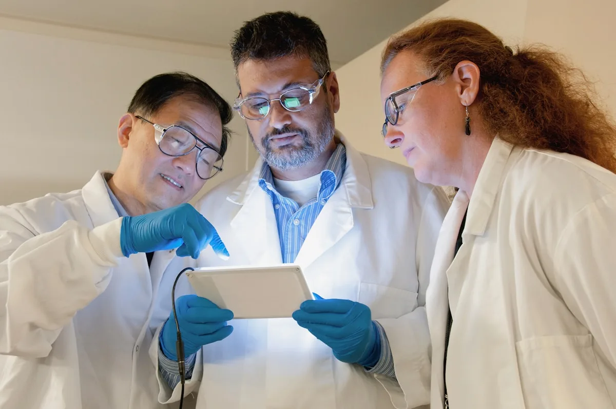 Researchers in lab coats reviewing data on screen