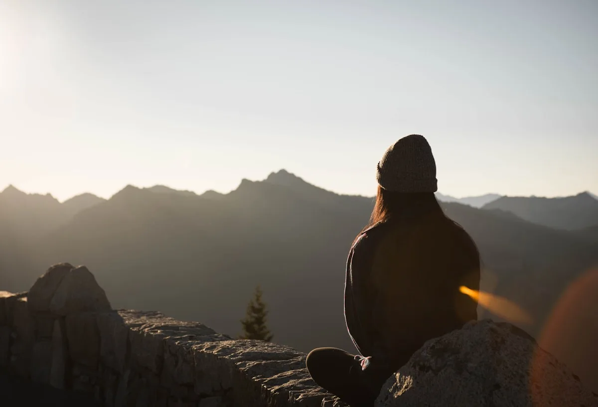 Person peacefully sitting in nature at sunset